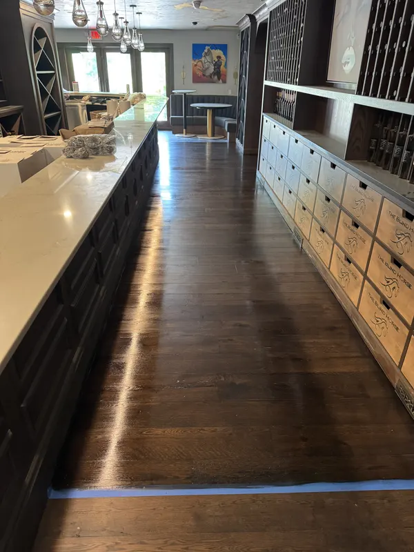 Dark-stained wide-plank white oak floor running between a bar and wine storage, Cedarburg, WI