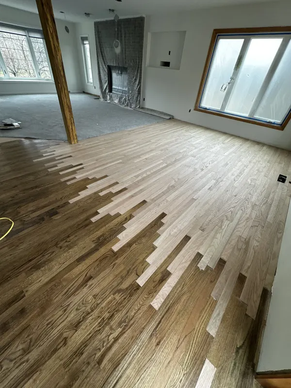 New hardwood boards weaved into an existing floor across an open room, Menomonee Falls, WI