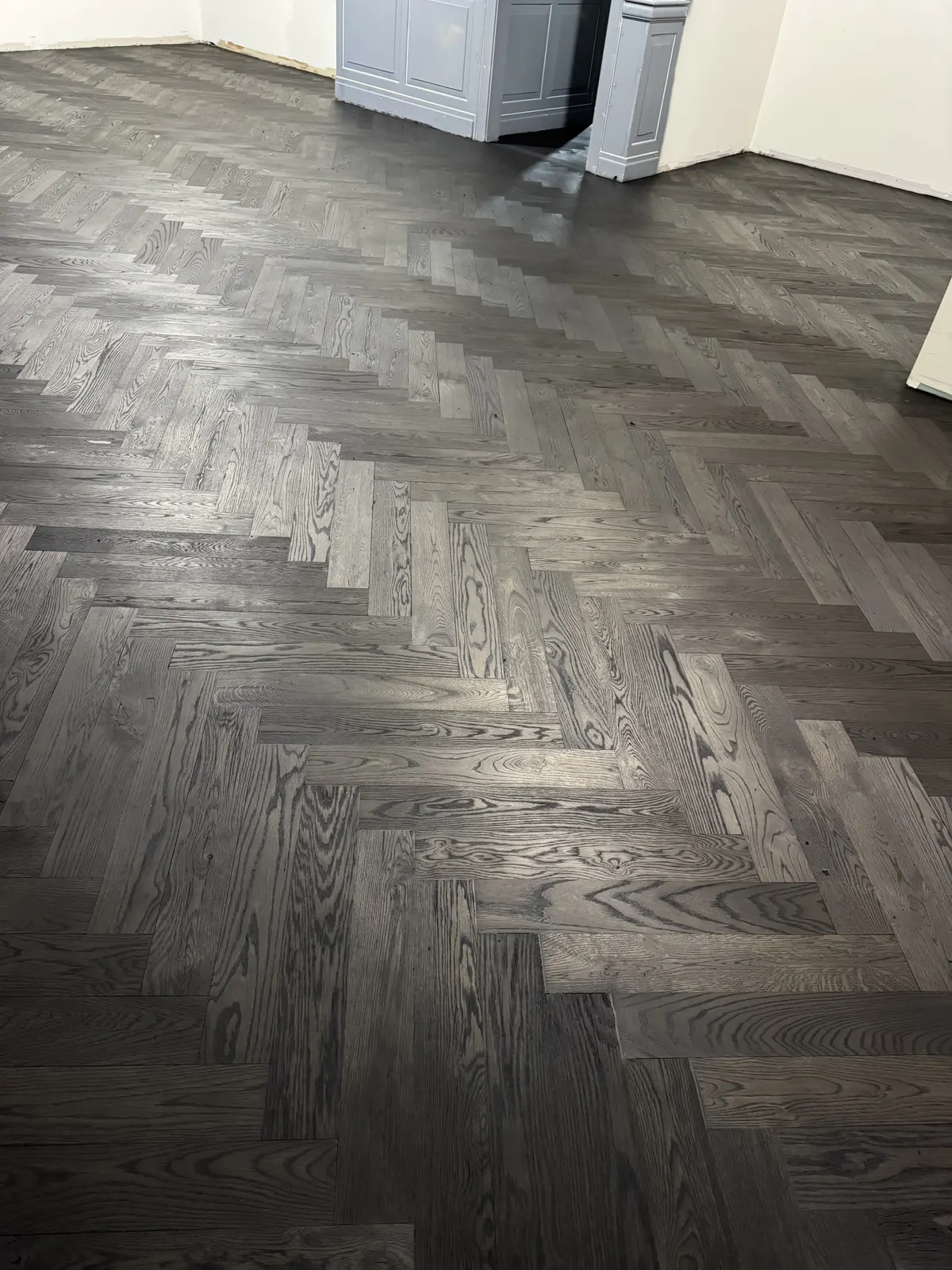 Dark stain on a sanded herringbone wood floor